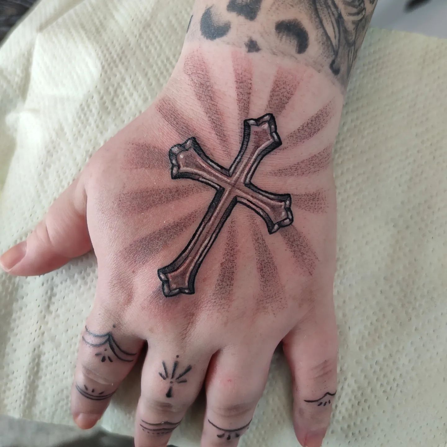 Hand tattoos are those who are bold since it is a part of the body that is most seen. In this tattoo, a relatively big cross is used. Can you spot these white thin lines inside of it? They make the cross gorgeous as well as the light shades behind it.