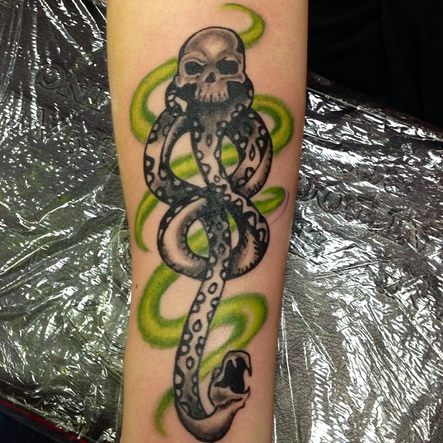 Thin and long death eater tattoo will take your arm to a whole different level! Shading details are amazing with a green swirl in the background. When all of these come together, a stunning tattoo is created.