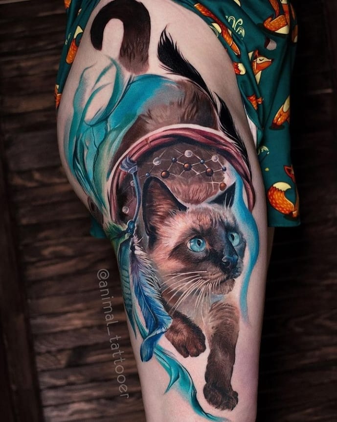 Who can say no to a fun tattoo? Cats are great and weird animals, right? You can show their weirdness in your dream catcher tattoo, too. The cat seems like it is stuck in the dream catcher and it is super cute.